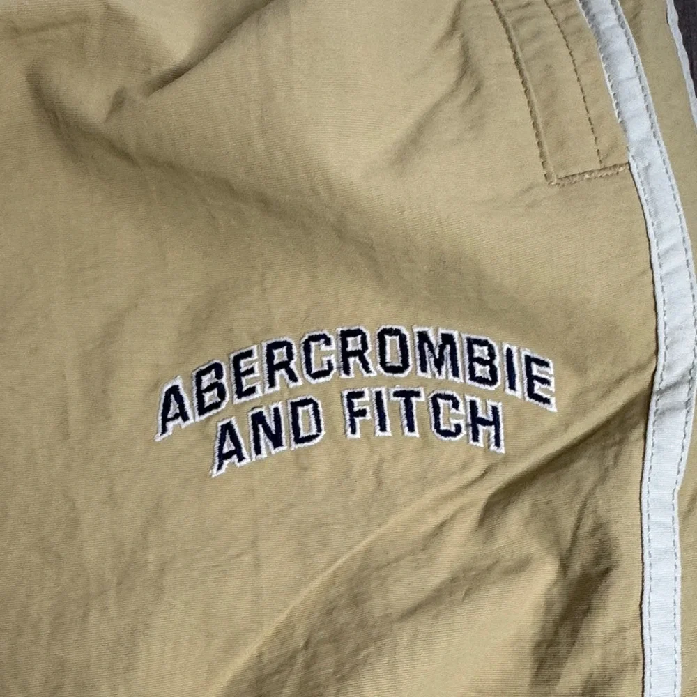 Vintage 90’s  Y2K Abercrombie and Fitch tan track pants with white stripes.